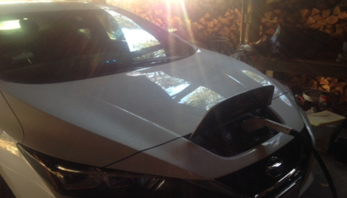 Front view of white vehicle being charged at an electric charger