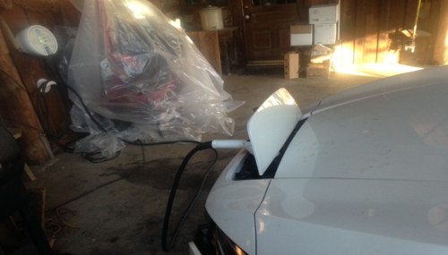 Side view of white vehicle being charged at an electric charger